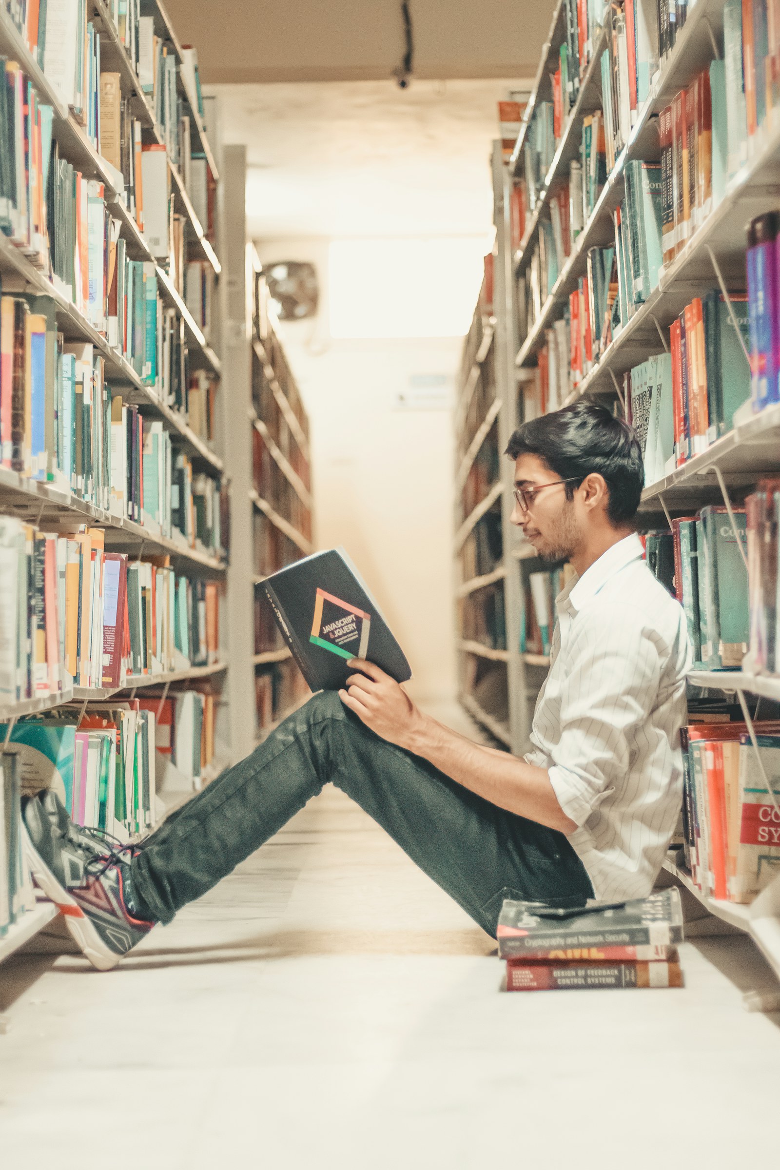 A student reading between library shelves