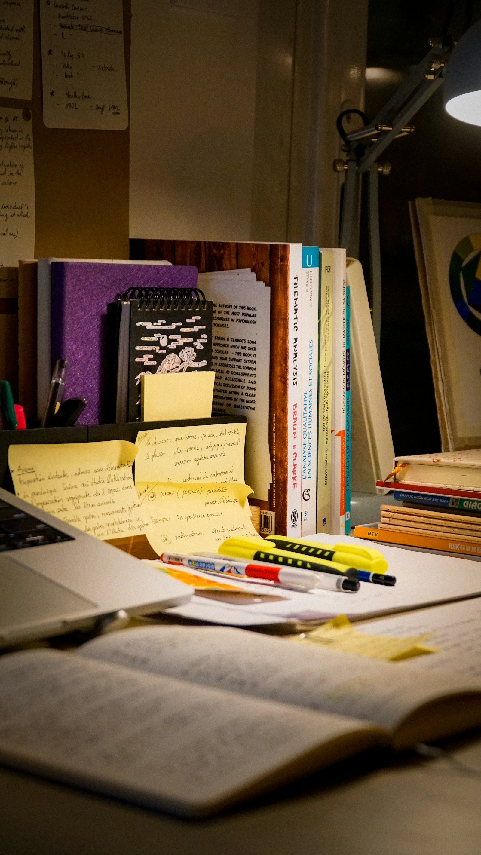 Research books, handwritten notes, and a laptop on a study desk